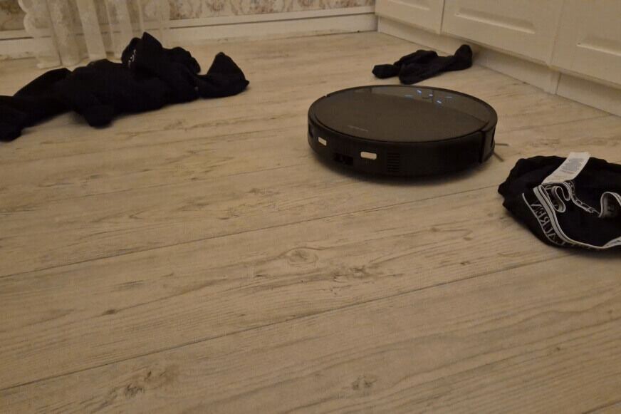 Roborock Saros 10R umfährt Ladekabel auf einem Holzboden